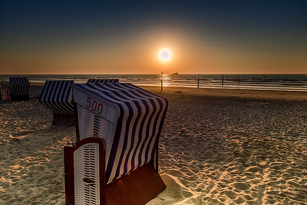 Strandkörbe welche mit einen phantastische Sonnenuntergang am Strand überzeugen